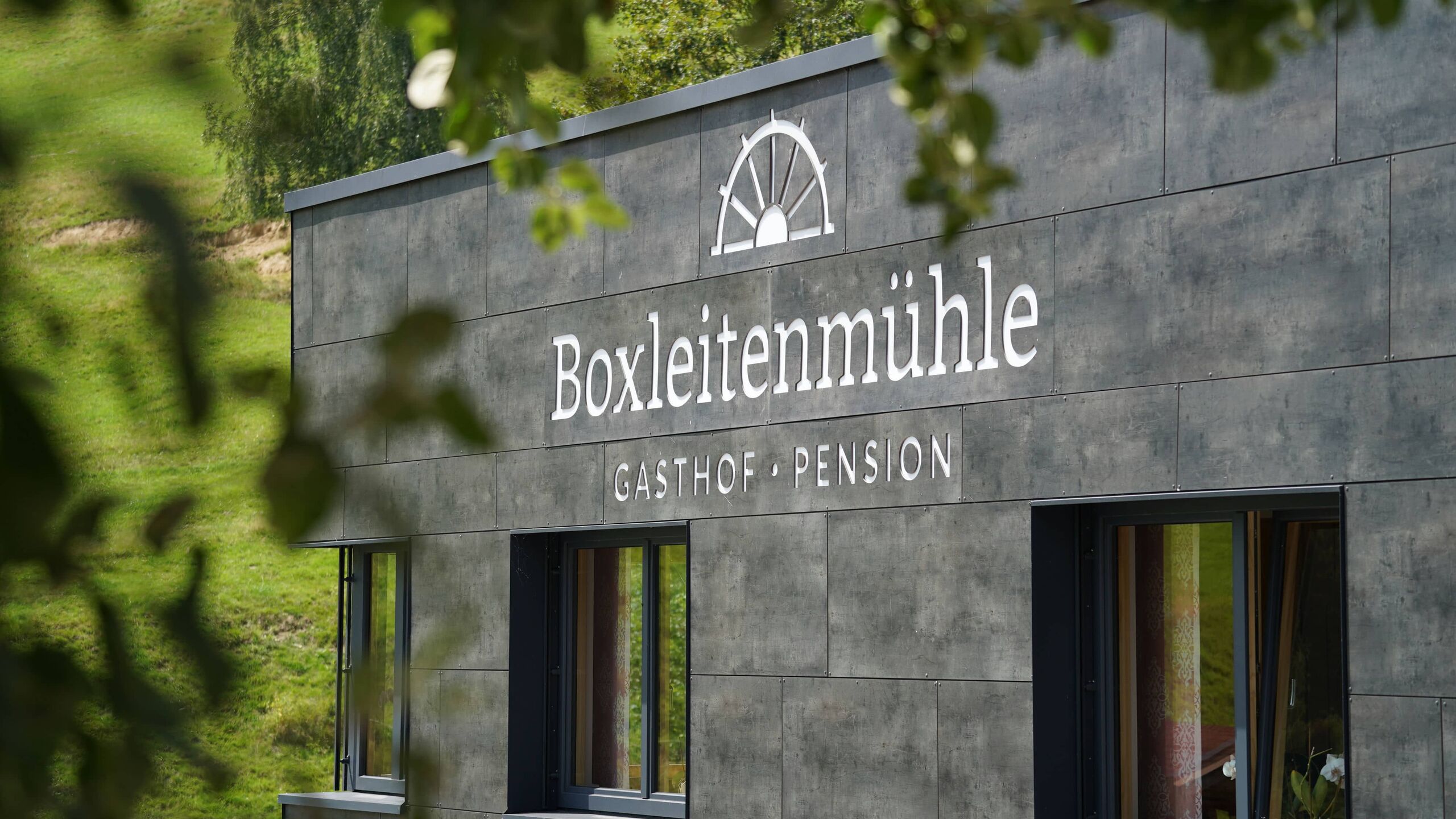 Eingang des Gasthofs Boxleitenmühle mit Schriftzug an der Schieferfassade